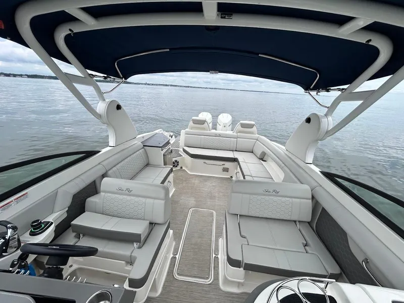 Slide: The Image of 2020 Sea Ray SDX 290 Outboard boat interior with spacious seating and canopy on calm water. - 13