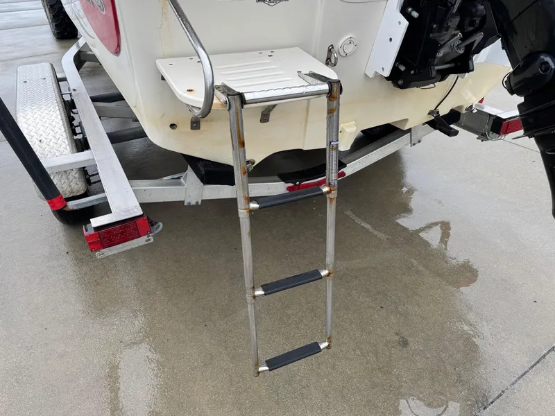 Slide: The Image of 2014 Carolina Skiff 218 DLV boat with ladder on trailer, wet pavement. - 20