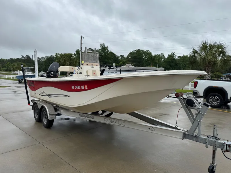 Slide: The Image of 2014 Carolina Skiff 218 DLV boat on trailer, parked outdoors on a cloudy day. - 4