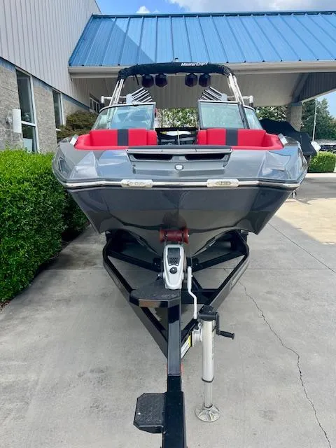 Slide: The Image of 2021 MasterCraft X24 boat on trailer, gray with red accents, parked outdoors. - 4