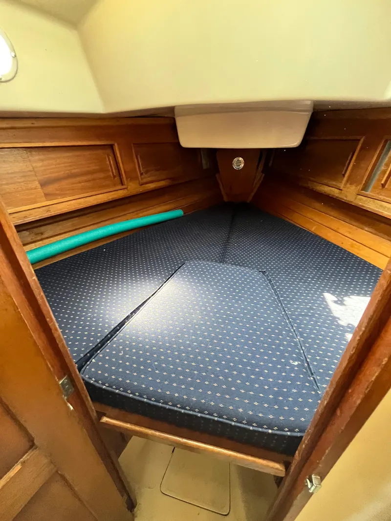 Slide: The Image of 1978 Bristol 29.9 sailboat cabin with blue cushioned V-berth and wooden interior. - 16