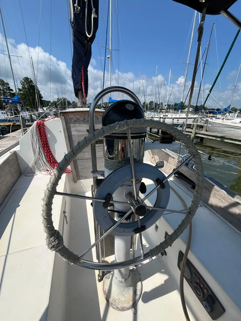 Slide: The Image of 1978 Bristol 29.9 sailboat helm with marina background, featuring a wrapped steering wheel. - 6