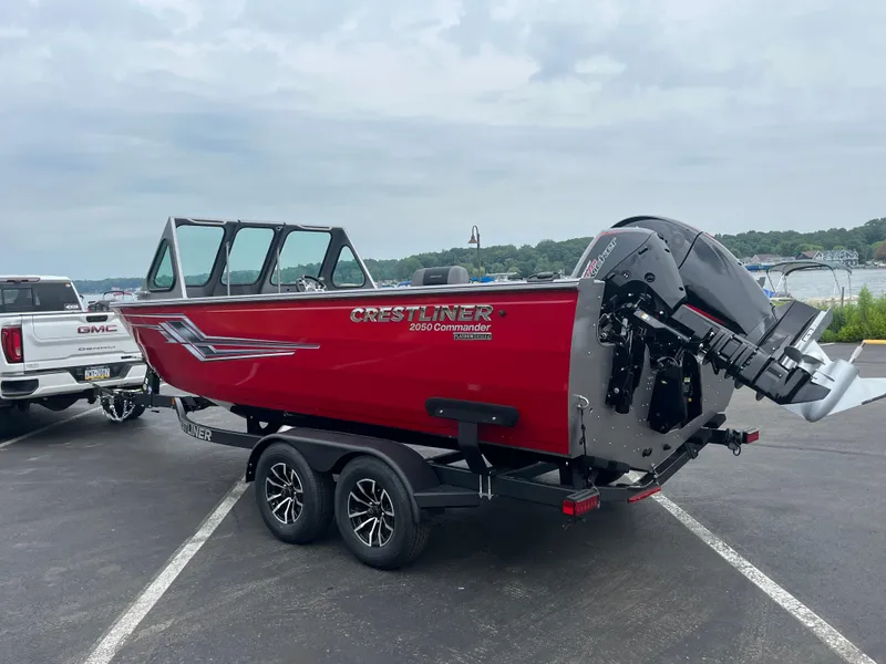 Slide: The Image of Red 2025 Crestliner 2050 Commander boat on trailer, parked near a lake. - 10