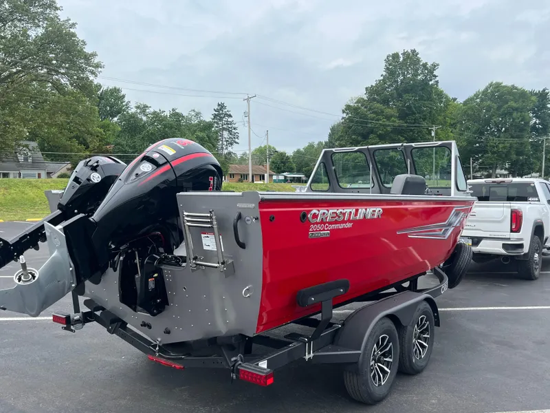 Slide: The Image of 2025 Crestliner 2050 Commander boat on trailer, red exterior, parked outdoors. - 2