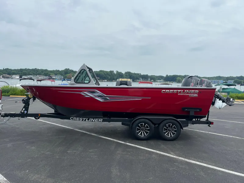 Slide: The Image of 2025 Crestliner 2050 Commander boat on trailer, red exterior, parked near waterfront. - 9