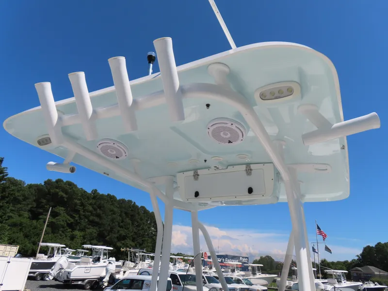 Slide: The Image of 2019 Sea Hunt Ultra 234 boat T-top with rod holders and speakers under clear blue sky. - 27