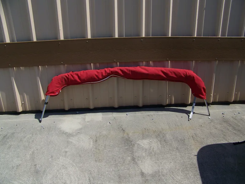 Slide: The Image of Red boat bimini top frame for 2001 Crownline 180 BR, leaning against a wall. - 3