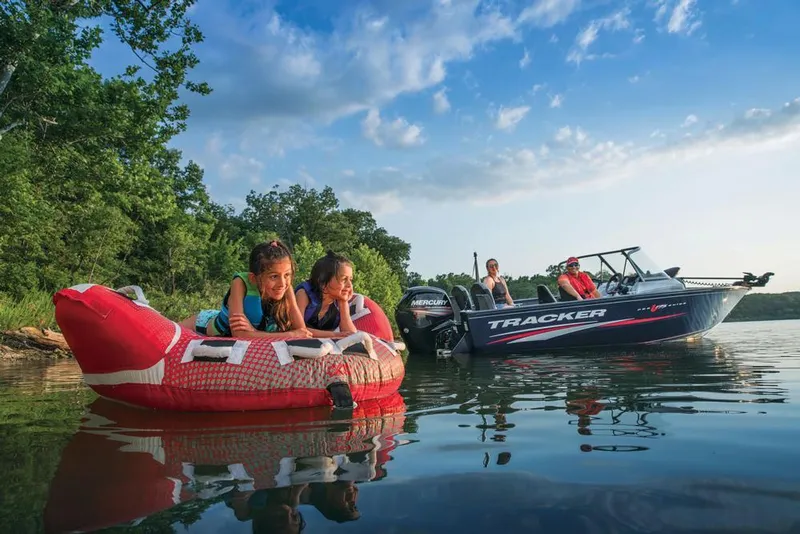 Slide: The Image of 2019 Tracker Pro Guide V-175 Combo boat on lake with kids tubing nearby. - 35