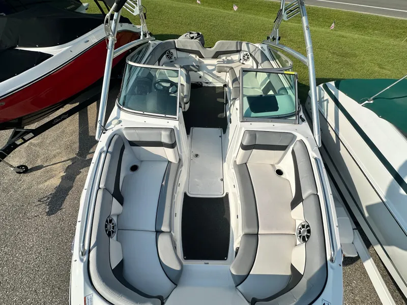 Slide: The Image of 2012 Yamaha Boats 212X with spacious seating and sleek design, parked on pavement. - 17