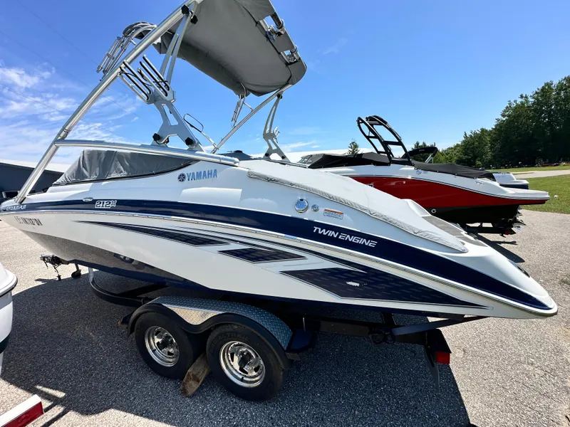 Slide: The Image of 2012 Yamaha Boats 212X twin-engine boat on trailer, parked outdoors under clear sky. - 7