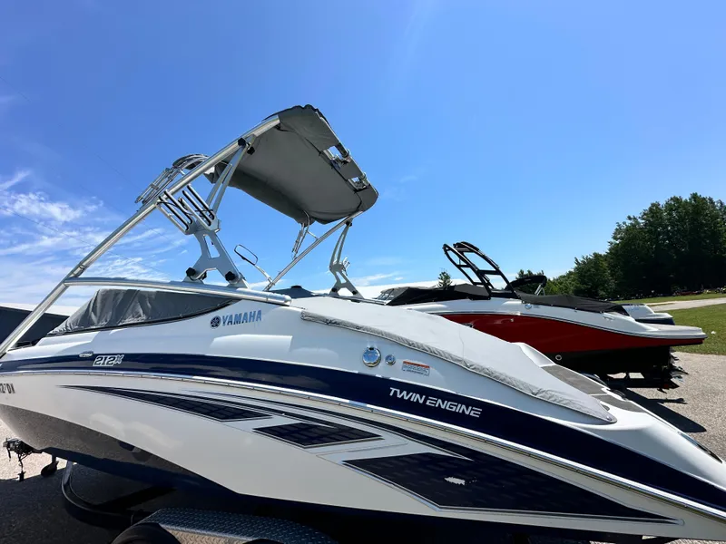 Slide: The Image of 2012 Yamaha Boats 212X with twin engines, parked outdoors under clear blue sky. - 8