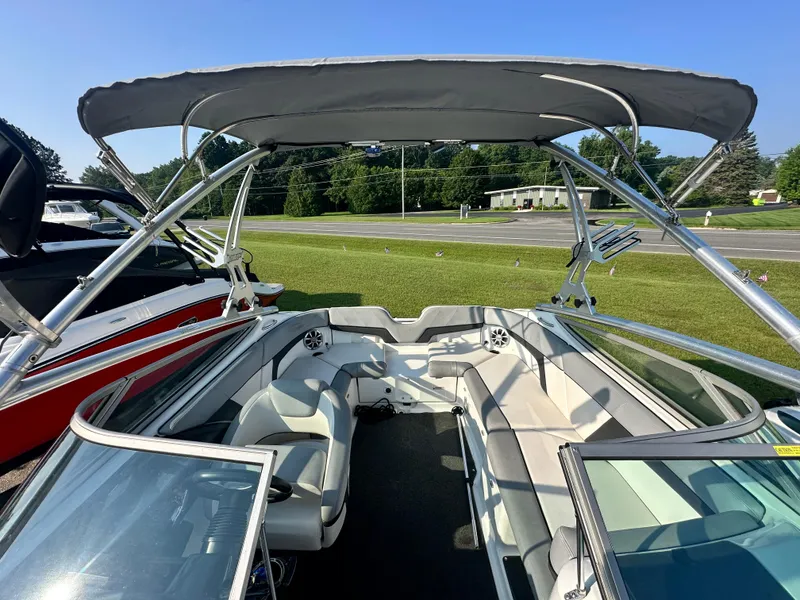 Slide: The Image of 2012 Yamaha Boats 212X interior with seating and canopy, parked on grass. - 9