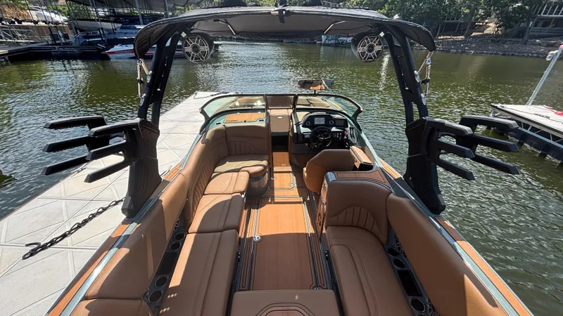 Slide: The Image of 2025 MB B52 25 Alpha boat interior with tan seating and advanced audio system on a lake. - 14