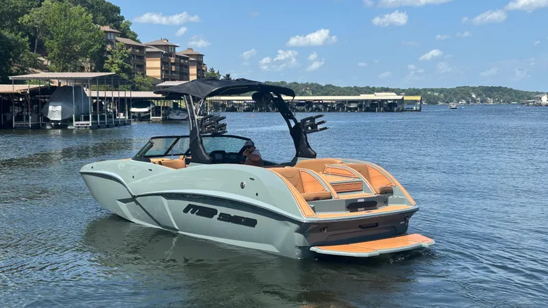 Slide: The Image of 2025 MB B52 25 Alpha boat on a scenic lake with docks and buildings. - 7