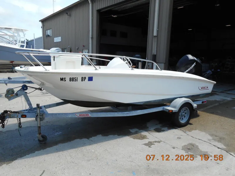 Slide: The Image of 2010 Boston Whaler 150 Super Sport boat on trailer outside a warehouse. - 3