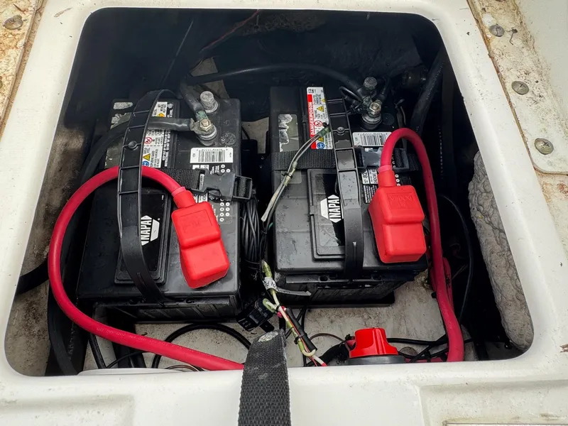 Slide: The Image of 2016 Sea Hunt BX22 boat battery compartment with dual NAPA batteries and red cables. - 9