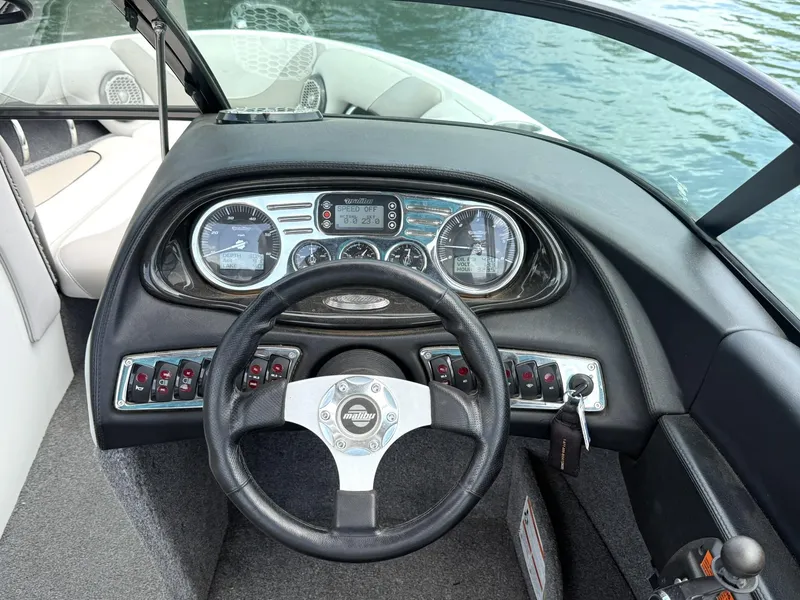 Slide: The Image of Steering wheel and dashboard of a 2012 Malibu 21 Ride boat on water. - 10