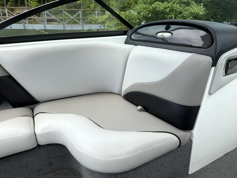 Slide: The Image of Interior seating of a 2012 Malibu 21 Ride boat, featuring white and gray upholstery. - 8