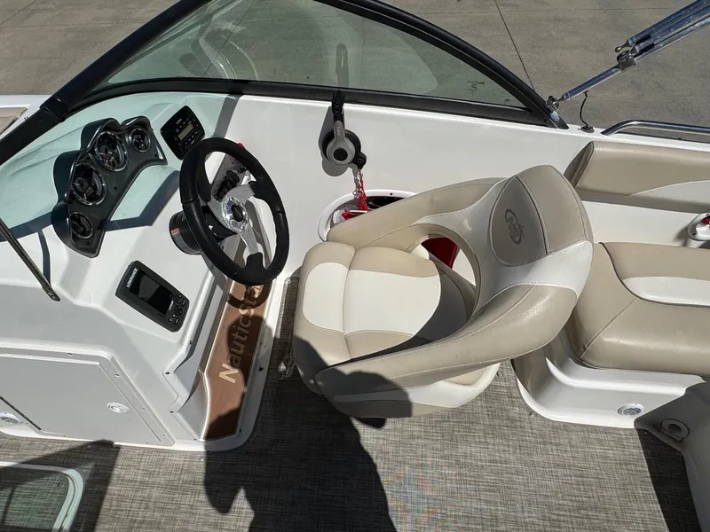 Slide: The Image of 2017 NauticStar 203 DC boat interior with steering wheel and beige seating. - 12