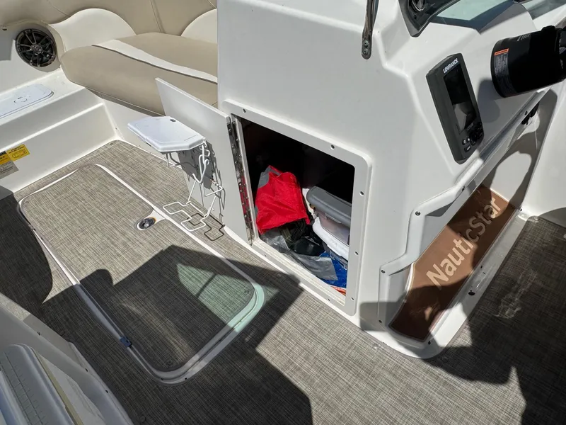 Slide: The Image of 2017 NauticStar 203 DC boat interior with storage compartment and seating area. - 13