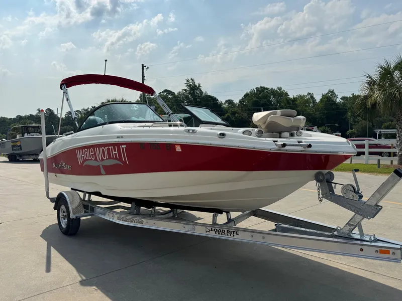 Slide: The Image of 2017 NauticStar 203 DC boat on trailer, red and white design, sunny day. - 2