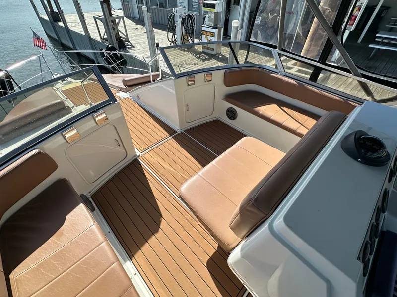 Slide: The Image of 1996 Carver 38 Santego boat interior with brown seating and wood flooring at dock. - 16