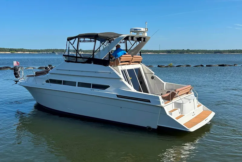 Slide: The Image of 1996 Carver 38 Santego yacht on calm water, featuring a spacious deck and canopy. - 3