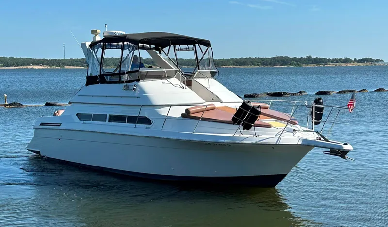 Slide: The Image of 1996 Carver 38 Santego yacht cruising on a calm lake under a clear blue sky. - 11