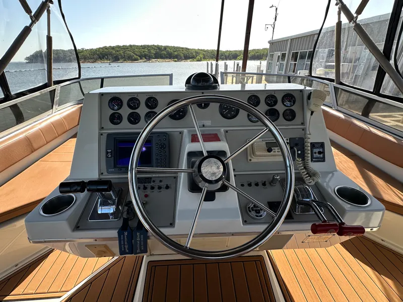 Slide: The Image of 1996 Carver 38 Santego helm with steering wheel, gauges, and controls, docked by the water. - 13