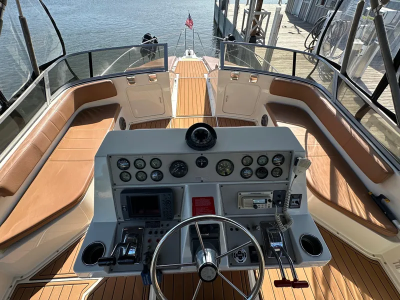 Slide: The Image of 1996 Carver 38 Santego yacht helm with controls, gauges, and seating, docked by the water. - 14