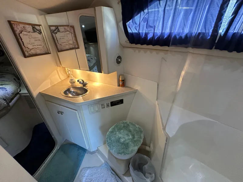 Slide: The Image of 1996 Carver 38 Santego yacht bathroom with sink, mirror, and blue curtains. - 49