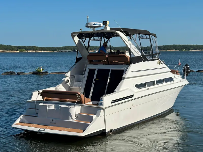 Slide: The Image of 1996 Carver 38 Santego yacht cruising on a serene lake under clear blue skies. - 7