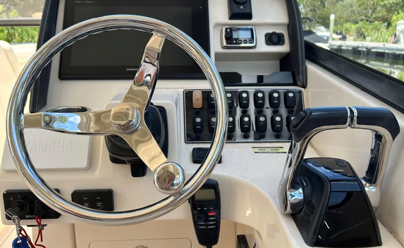 Slide: The Image of 2016 Grady-White Freedom 275 boat dashboard with steering wheel and controls. - 14