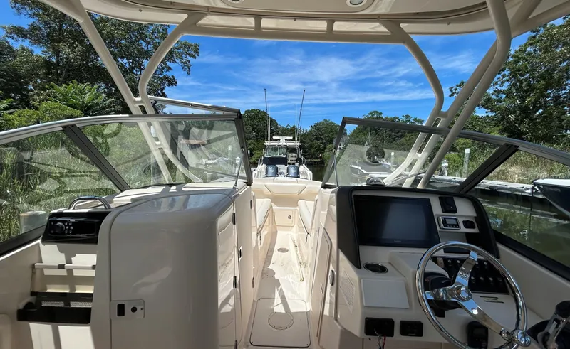 Slide: The Image of 2016 Grady-White Freedom 275 boat interior with steering wheel and dashboard, docked under blue sky. - 15