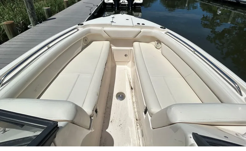 Slide: The Image of 2016 Grady-White Freedom 275 boat interior with white seating and dockside view. - 16