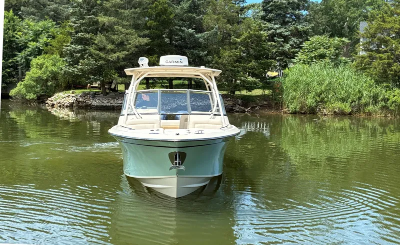 Slide: The Image of 2016 Grady-White Freedom 275 boat on calm water, surrounded by lush greenery. - 3