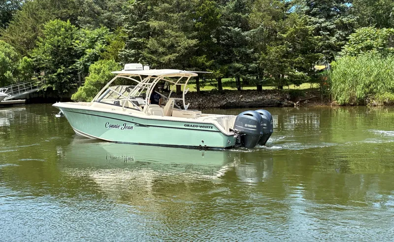 Slide: The Image of 2016 Grady-White Freedom 275 boat cruising on a serene lake surrounded by lush greenery. - 5