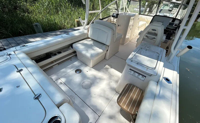 Slide: The Image of 2016 Grady-White Freedom 275 boat interior with seating and console, docked by greenery. - 8