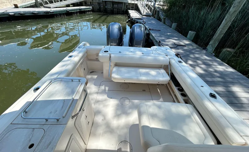Slide: The Image of 2016 Grady-White Freedom 275 boat interior with seating and twin engines at dock. - 9