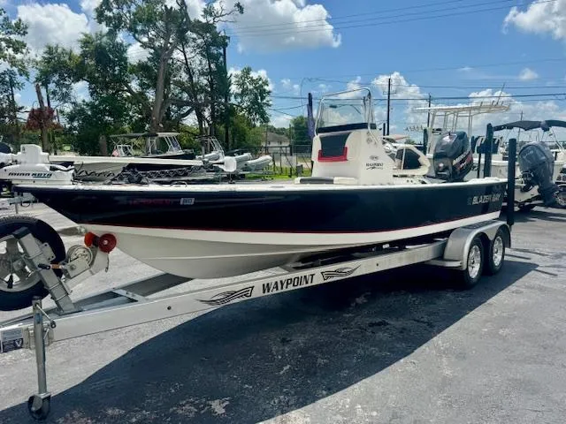 Slide: The Image of 2017 Blazer Bay 2170 boat on a Waypoint trailer, parked outdoors under a clear sky. - 6