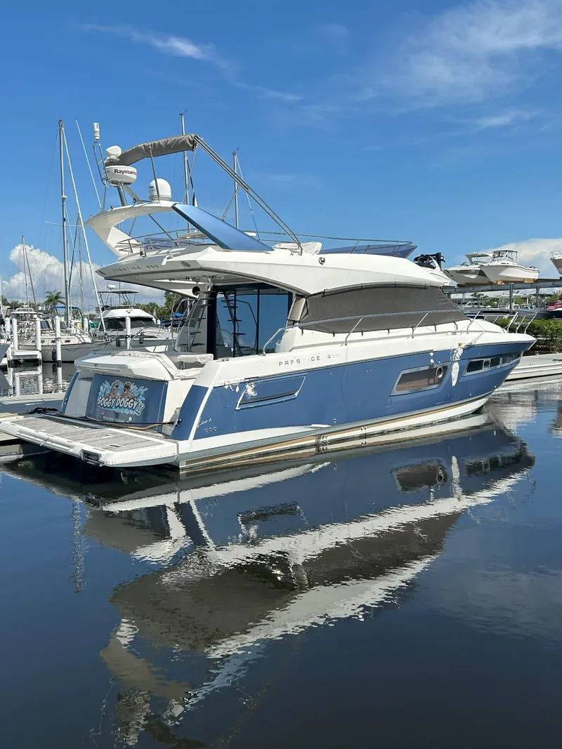 The Image of 2015 Prestige 450 Fly yacht docked, reflecting on calm water under a clear blue sky. - 1
