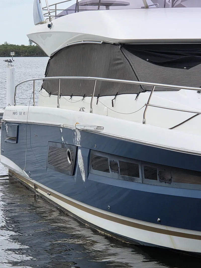 Slide: The Image of 2015 Prestige 450 Fly yacht with visible hull damage, docked on calm water. - 7