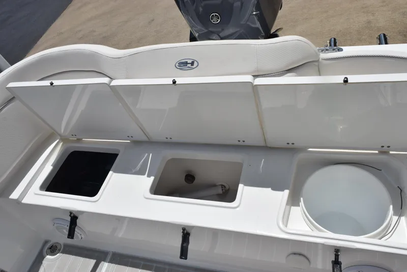 Slide: The Image of 2023 Sea Hunt Ultra 234 boat storage compartments with open lids, showcasing interior space. - 21