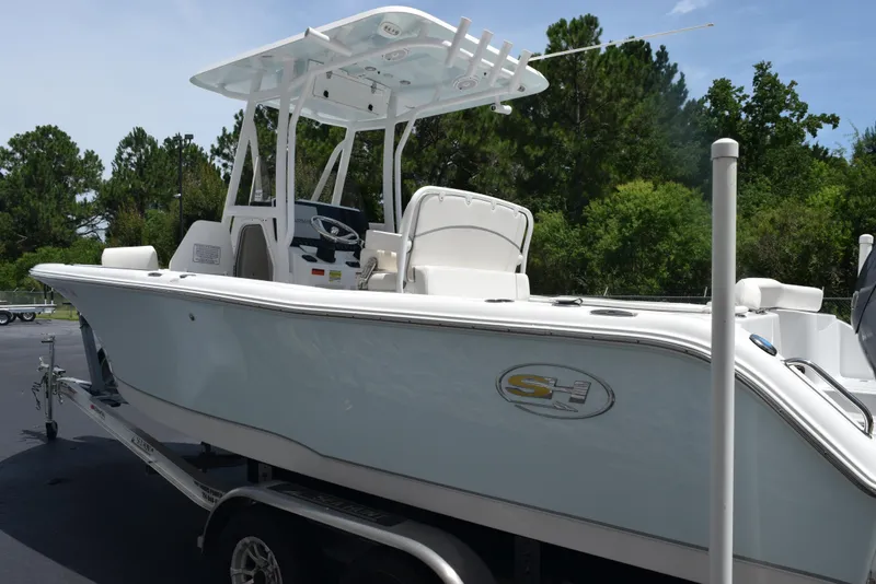 Slide: The Image of 2023 Sea Hunt Ultra 234 boat on trailer, parked outdoors with trees in background. - 6