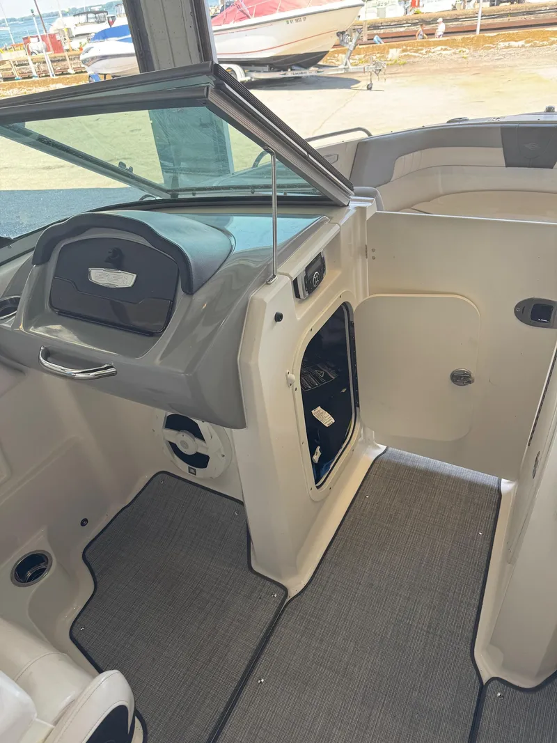 Slide: The Image of Interior of a 2021 Chaparral 23ssi boat, featuring helm and open storage compartment. - 13