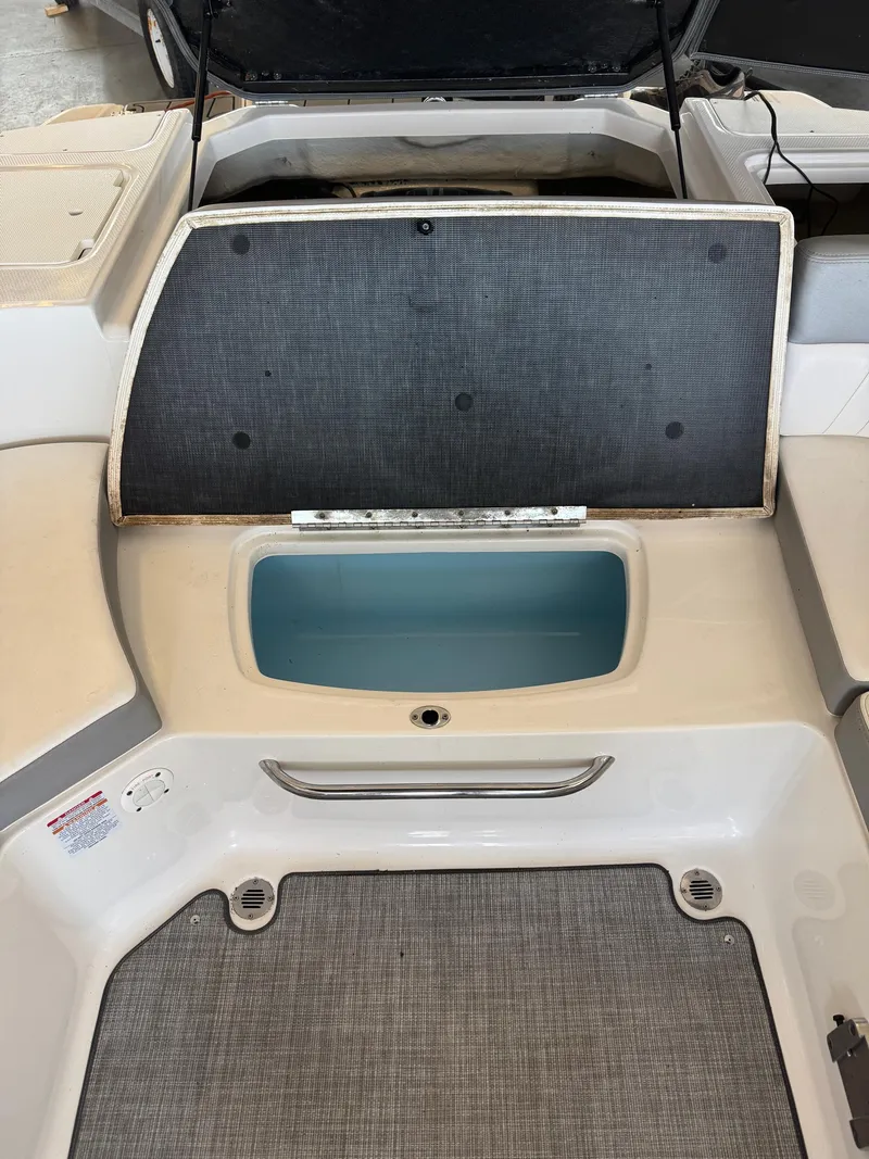 Slide: The Image of 2021 Chaparral 23ssi boat storage compartment with open lid, showcasing interior space. - 16