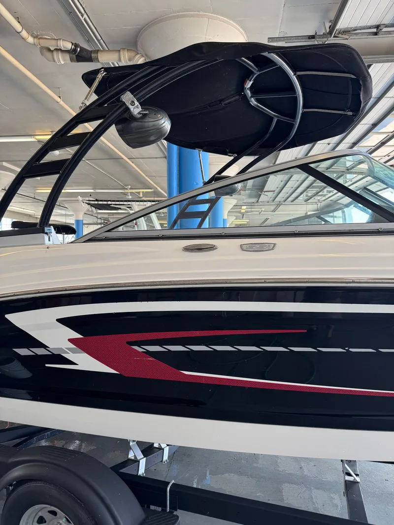Slide: The Image of 2021 Chaparral 23ssi boat with sleek black and red design in a covered storage area. - 2