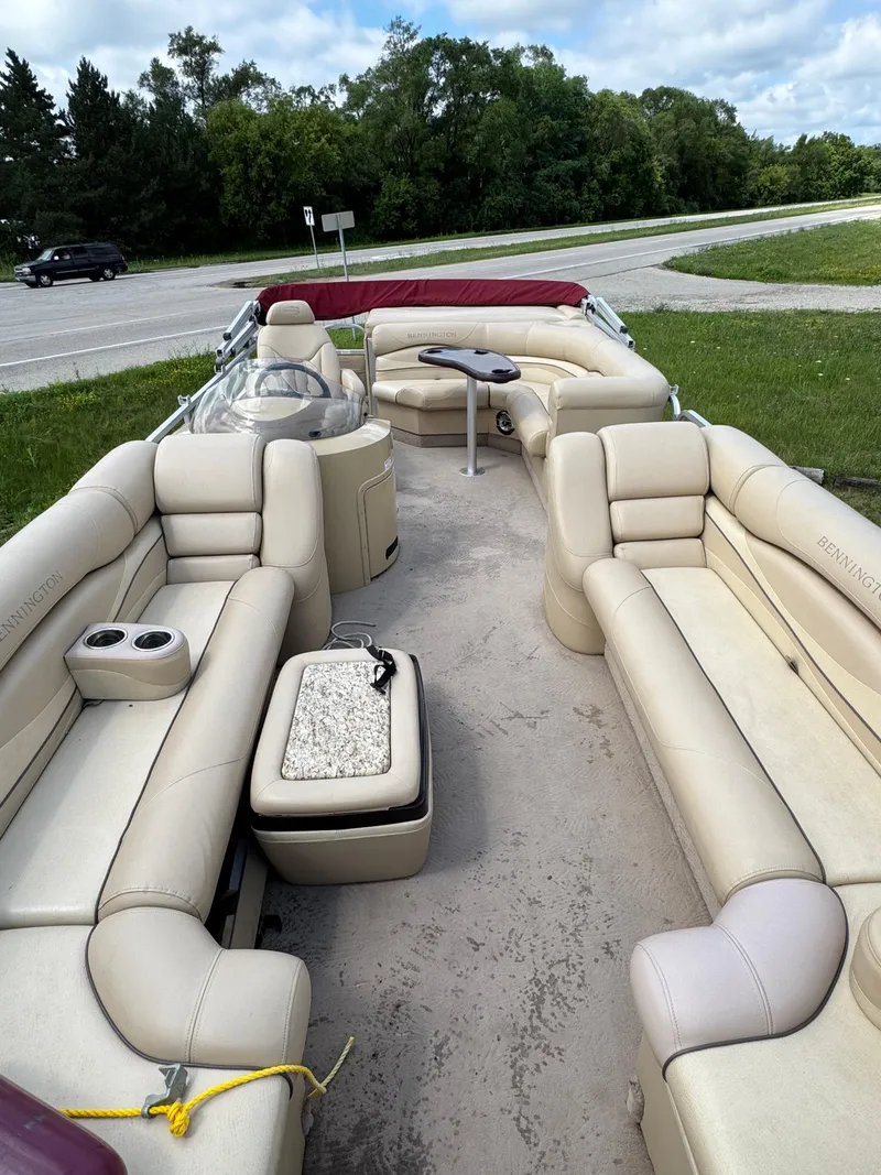 Slide: The Image of 2008 Bennington 2275RLi pontoon boat with beige seating and table, parked near a road. - 8