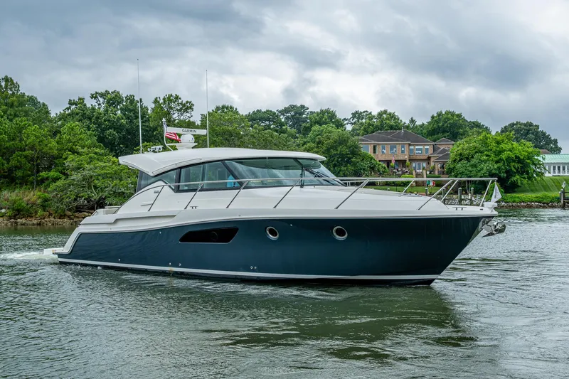 Slide: The Image of 2020 Tiara Yachts C44 Coupe cruising on a scenic waterway with lush greenery. - 17
