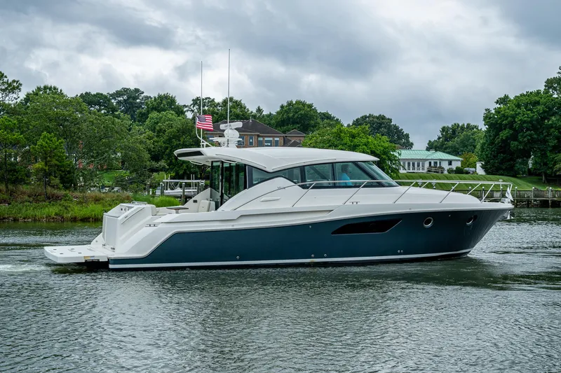 Slide: The Image of 2020 Tiara Yachts C44 Coupe cruising on a scenic waterway with lush greenery. - 19